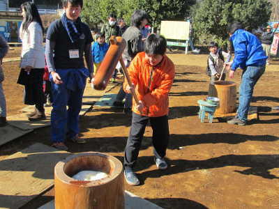 （写真）杵を振り上げて、もちつき体験をする男の子。