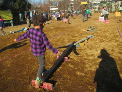 （写真）細長い棒の上をバランスをとって渡ろうとする子ども.jpg