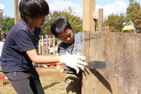 (写真)真剣な表情で板をノコギリで切る男の子