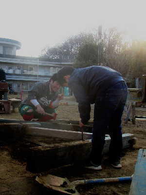 (写真)木材から釘を抜く男の子とそれを見守るスタッフ