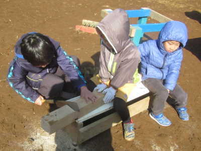 （写真）木材を協力してのこぎりで切る子ども