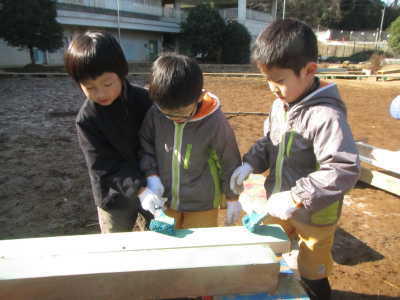（写真）木材にペンキを塗る子どもたち