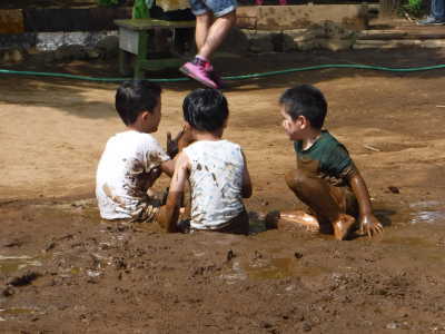 (写真)どろんこ遊びをする子どもたち。