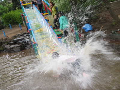 (写真)水しぶきをあげてウォータースライダーをすべる子ども。