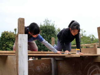 （写真）屋根に上って釘を打っている女の子